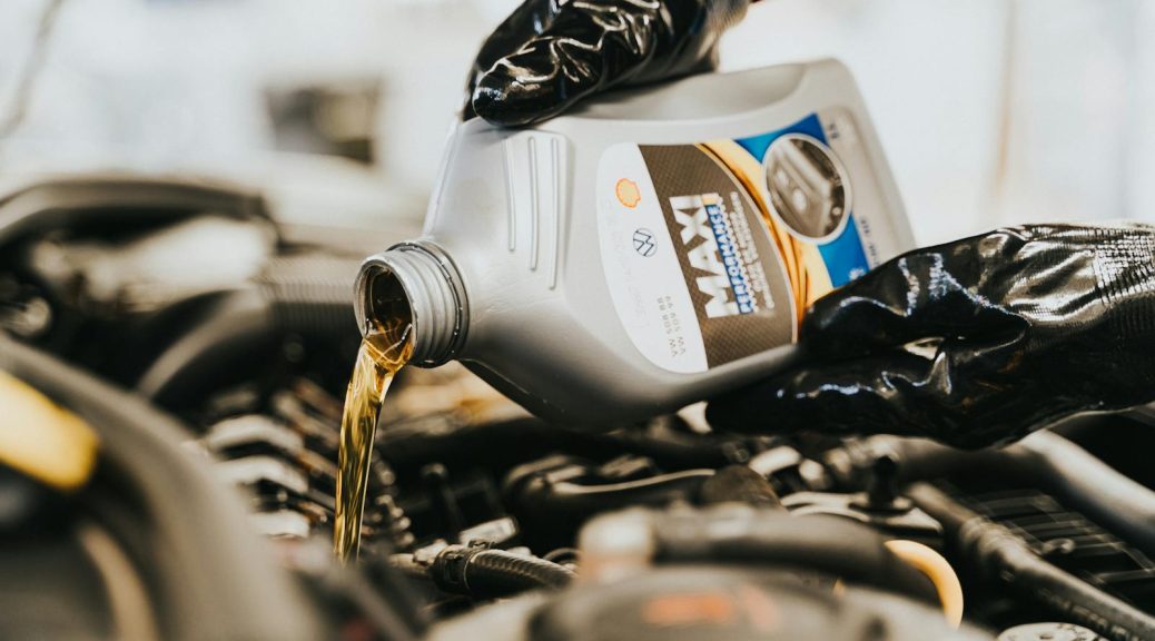 Close-up of a mechanic pouring engine oil into a car engine, highlighting maintenance work.