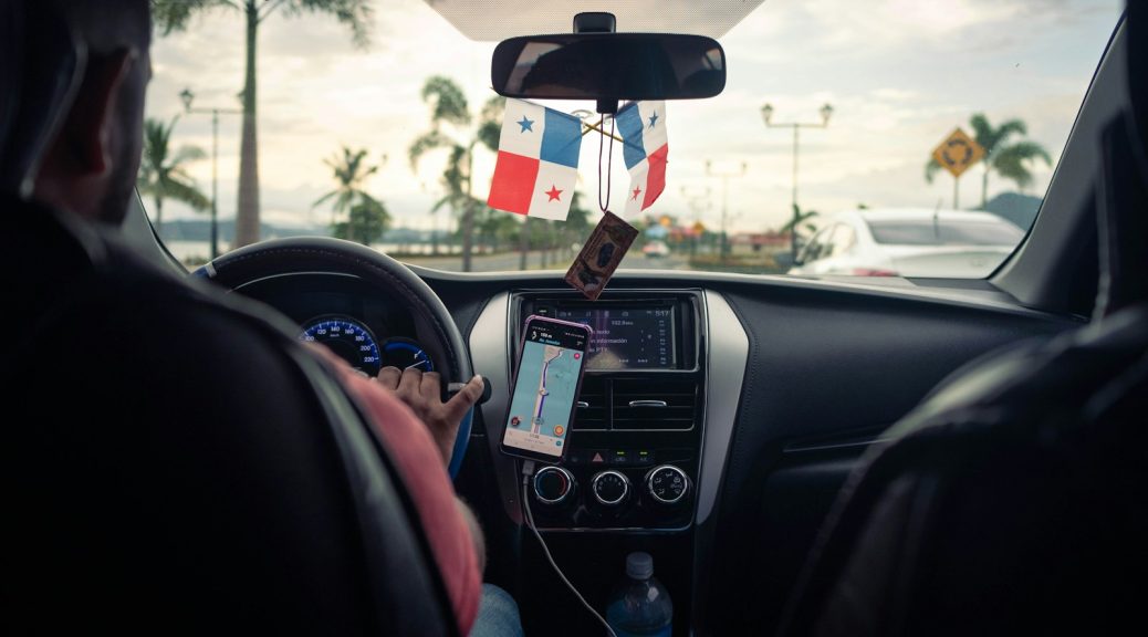 a man driving a car with a flag hanging from the dash