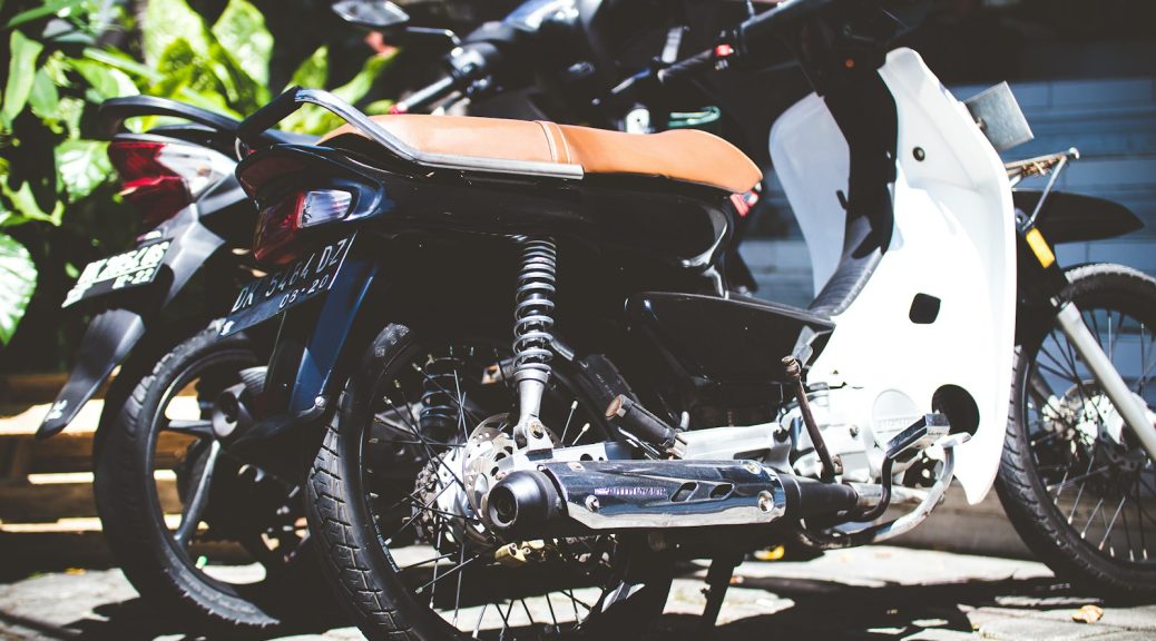 two white and black underbone motorcycles parked on ground near plant at daytime