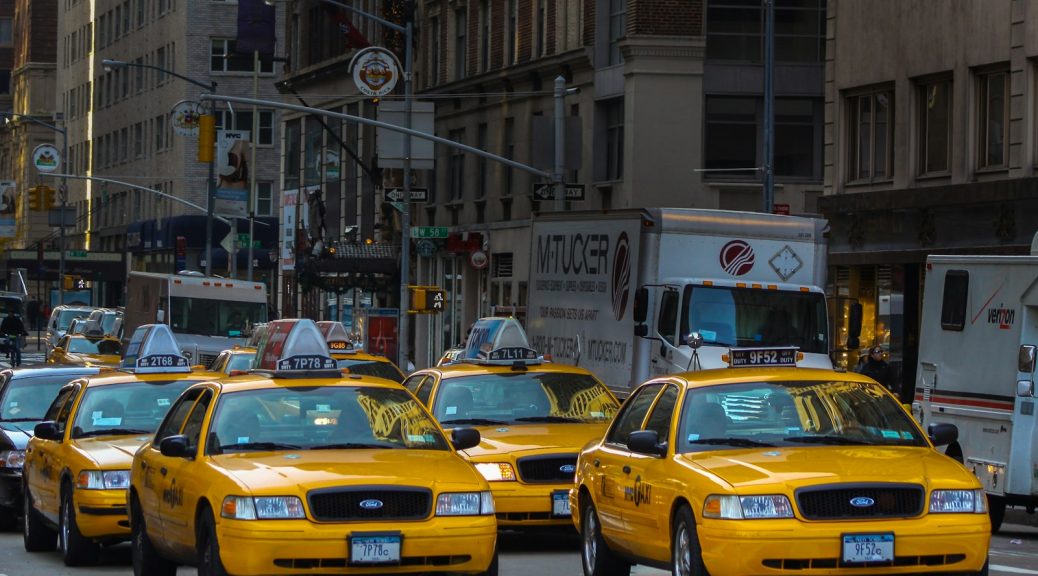 yellow taxi cab on road near white concrete building during daytime